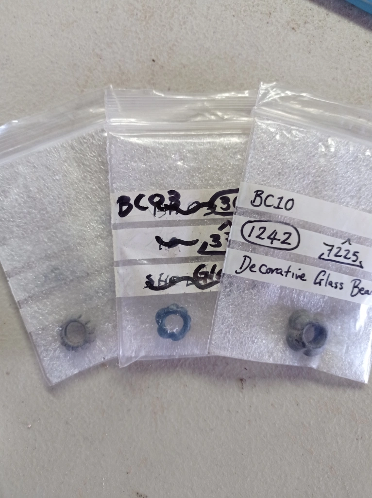 Small finds bags with three decorative blue beads, one per bag.